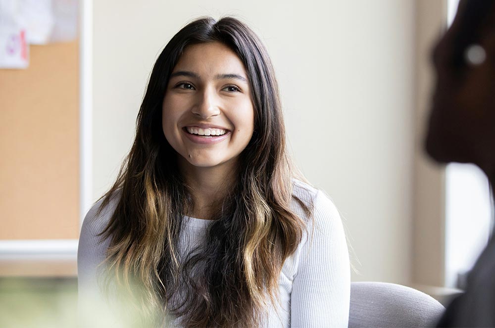 Smiling young woman with long hair listening attentively during a conversation in a bright room