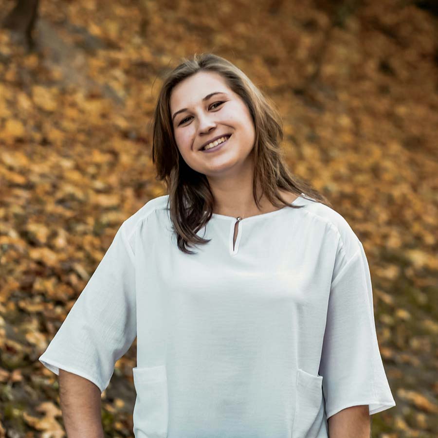 Smiling woman in a white blouse, portrait against a backdrop of autumn leaves